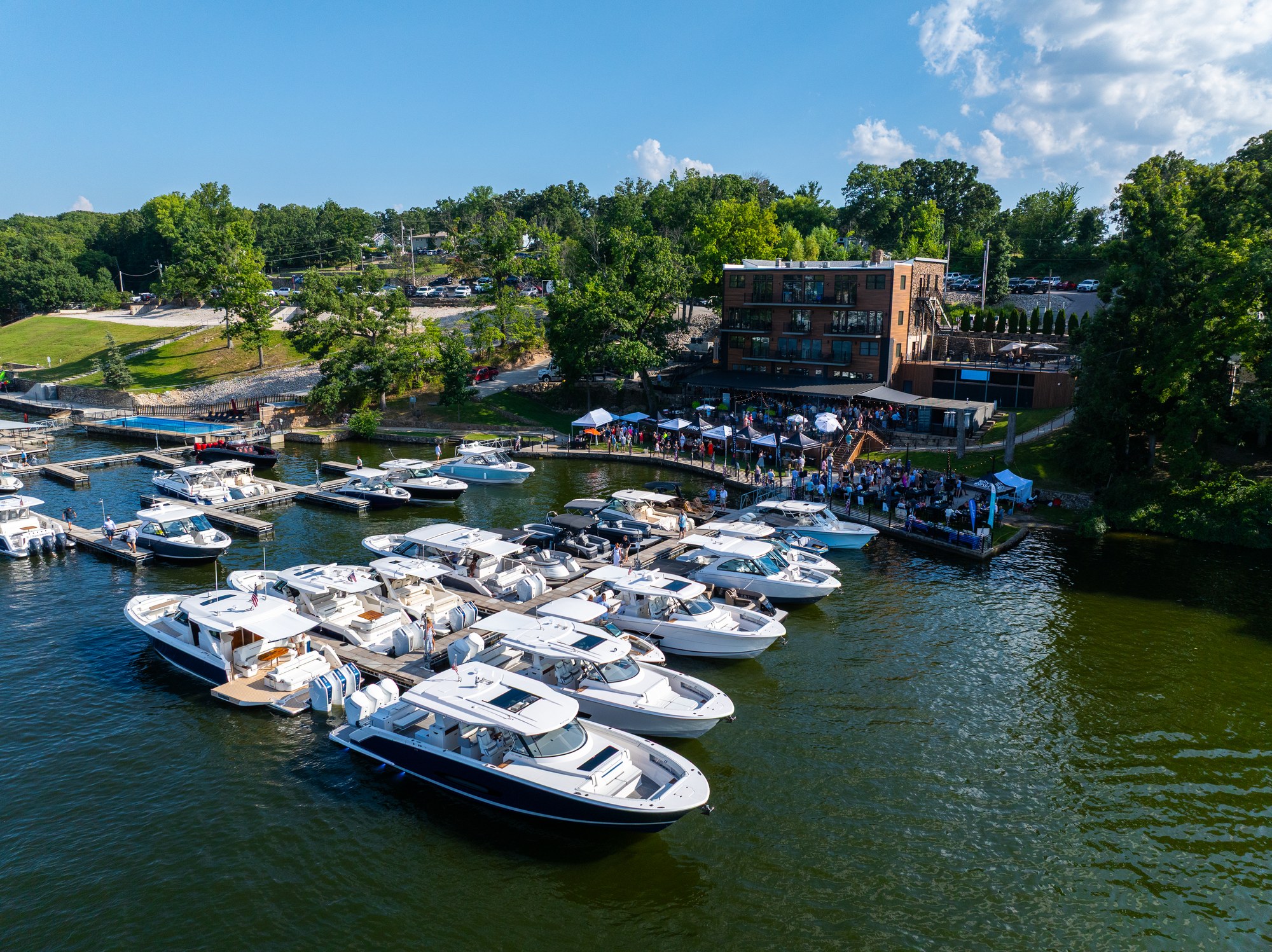 Aerial view of luxury yachts moored along the 1932 Reserve docks at the Yacht Gala on Lake of the Ozarks, with guests gathered on the waterfront terrace