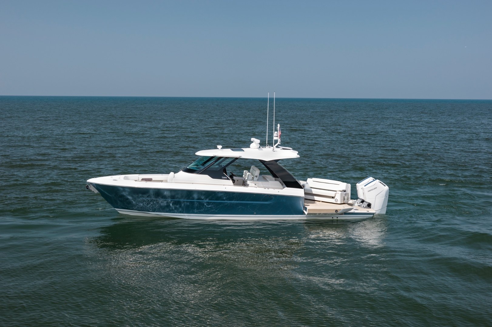 Tiara Yachts 39 LS running at speed across open water with a forested shoreline behind